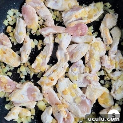 Chicken strips cooking on high heat with onions and garlic
