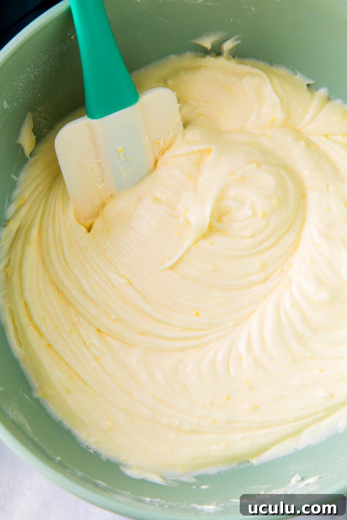 Close up of lemon frosting with cream cheese that's smooth in a mixing bowl.