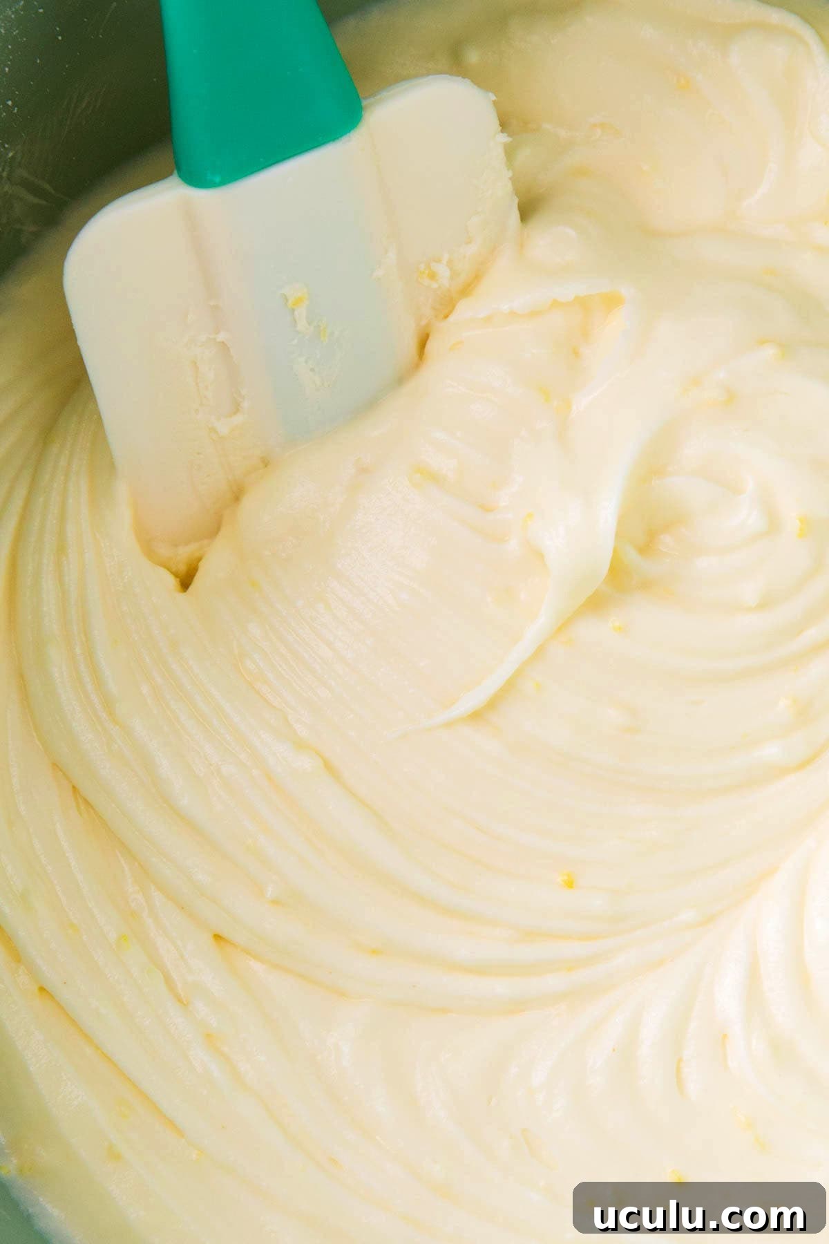 A frosting spatula scooping the best lemon cream cheese frosting made with fresh lemon juice and lemon zest for big lemon flavor.