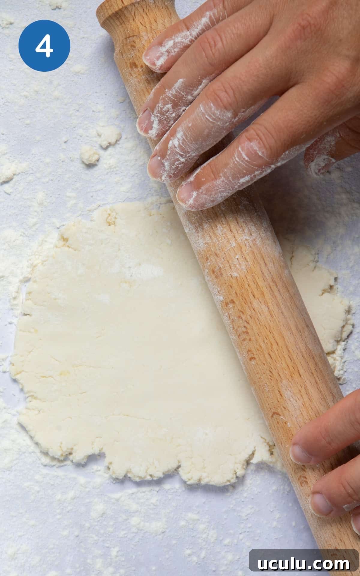 dough for naan being rolled out with rolling pin on floured surface.