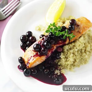 A fillet of salmon topped with blueberry sauce on a white plate.