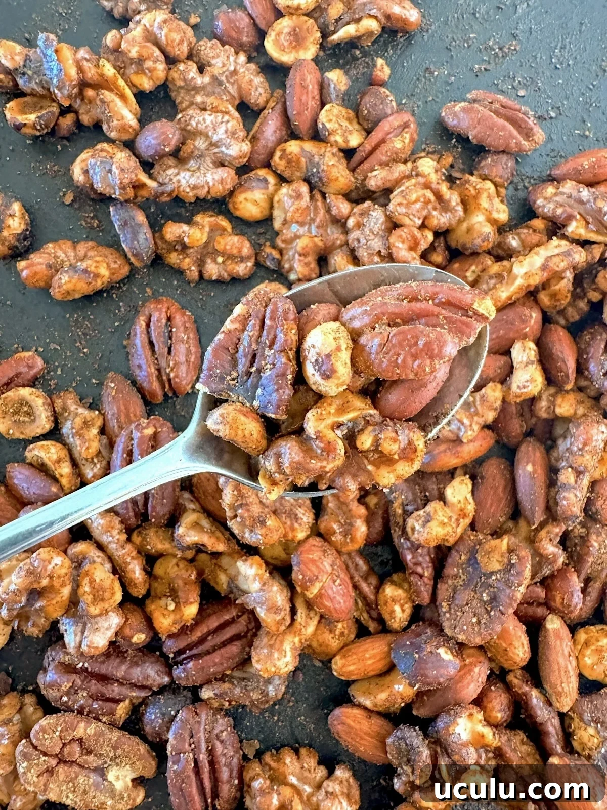 scooping nuts from pan with a spoon
