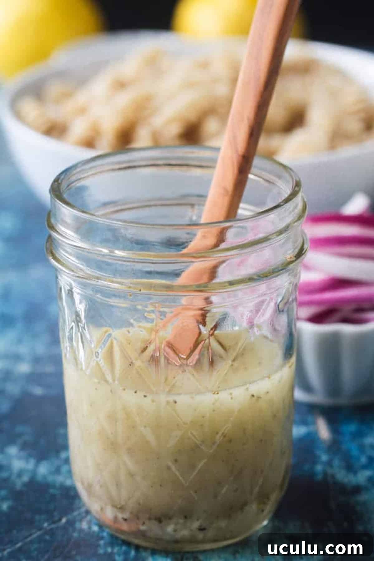 Small wooden spoon in a jar of lemon vinaigrette.