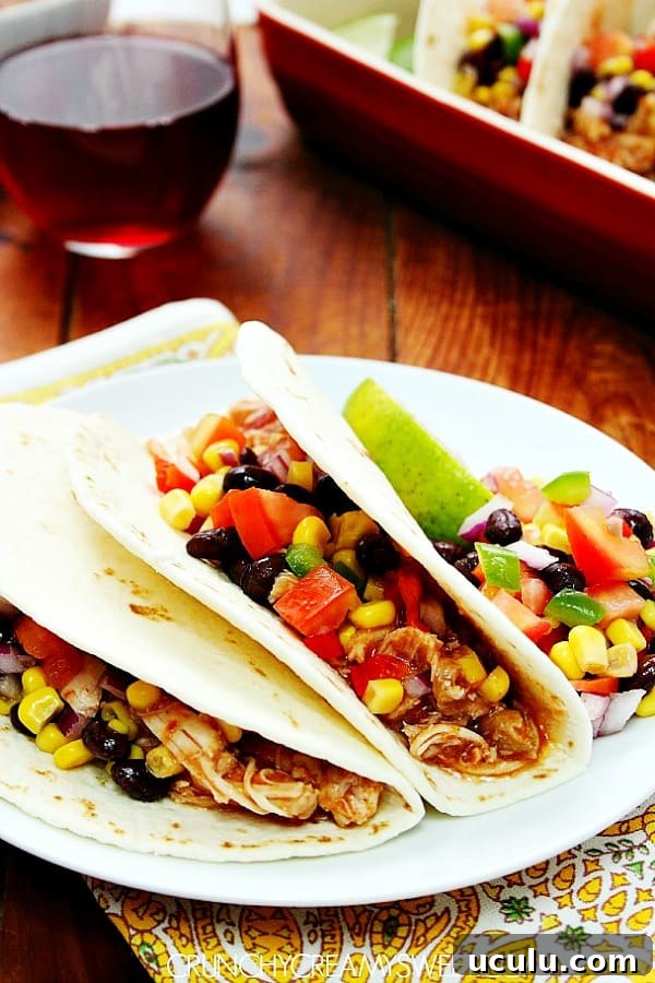 Two chicken tacos on white plate.