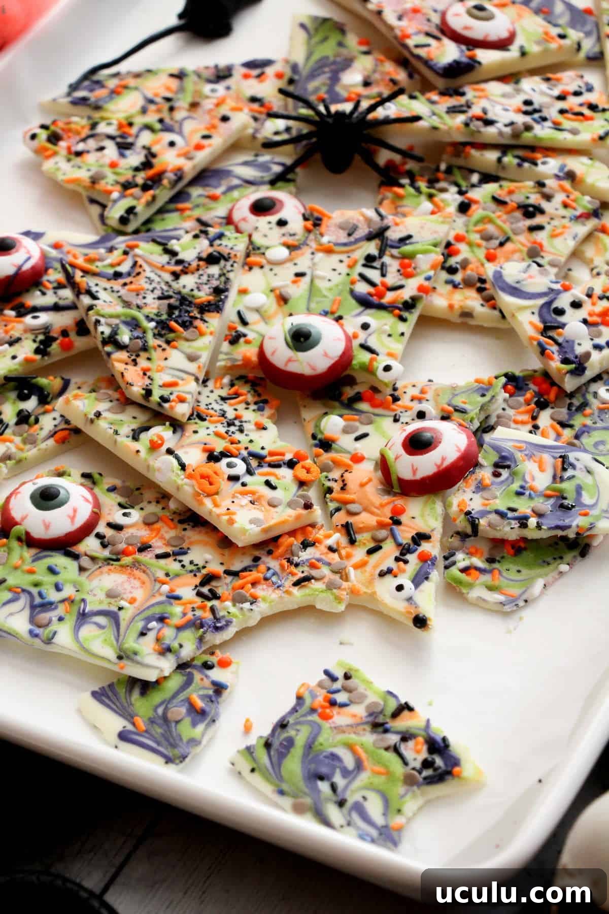 Halloween bark broken into pieces on white baking sheet