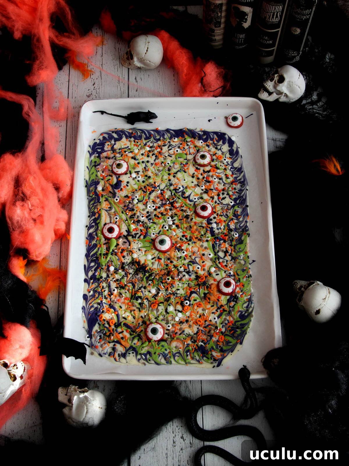 Halloween bark made from white chocolate placed on white baking sheet