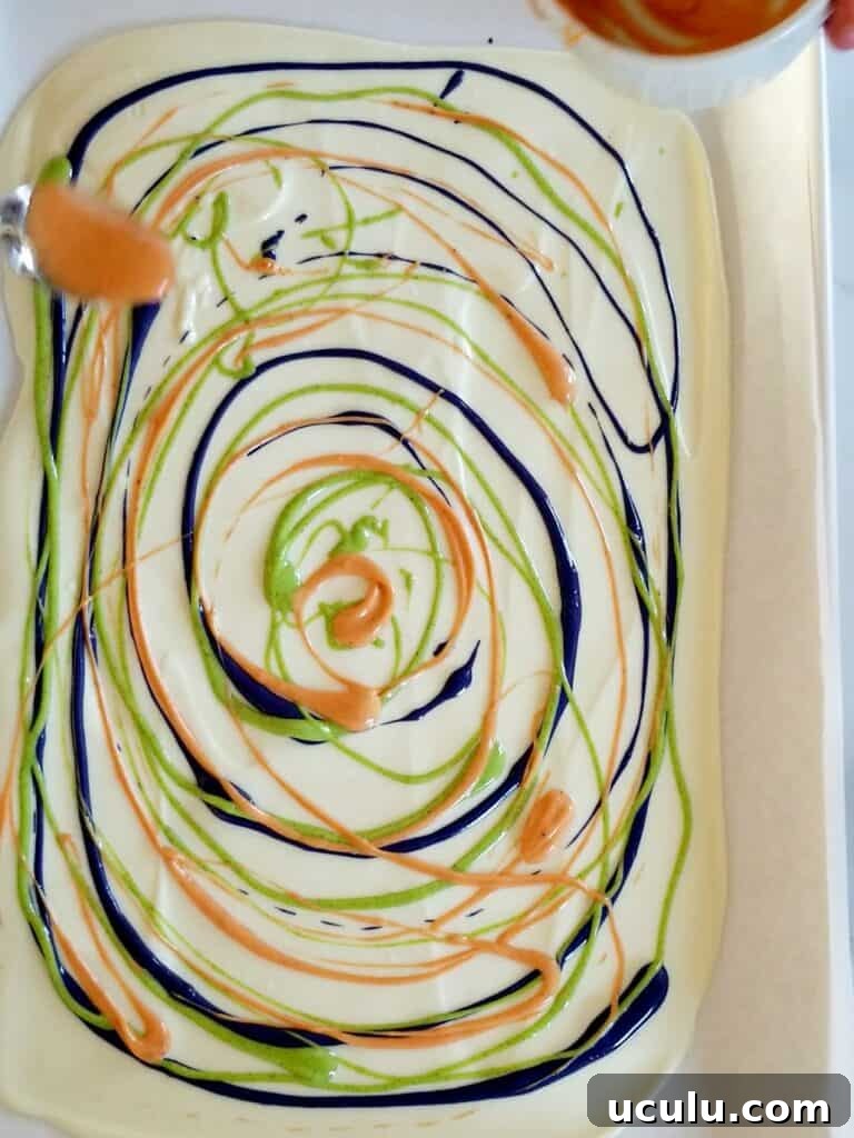 Melted white chocolate on baking sheet with another coloured chocolate dripped in circles