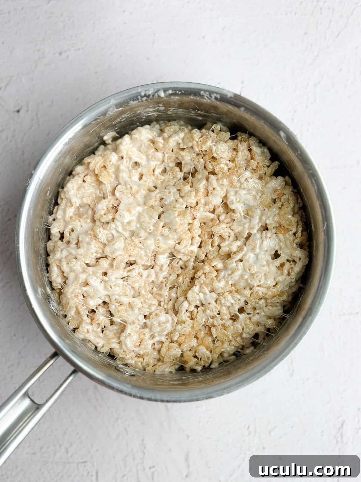 rice krispie cereal being stirred in to the marshmallows.