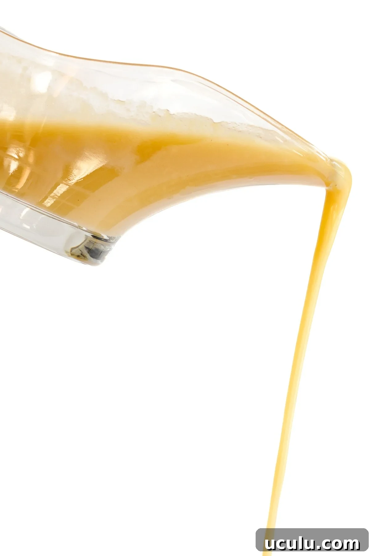Turkey gravy being poured from a glass gravy boat.