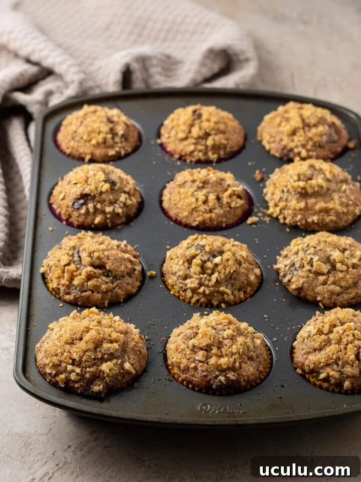 sour cream banana muffins with walnut topping in a muffin tin