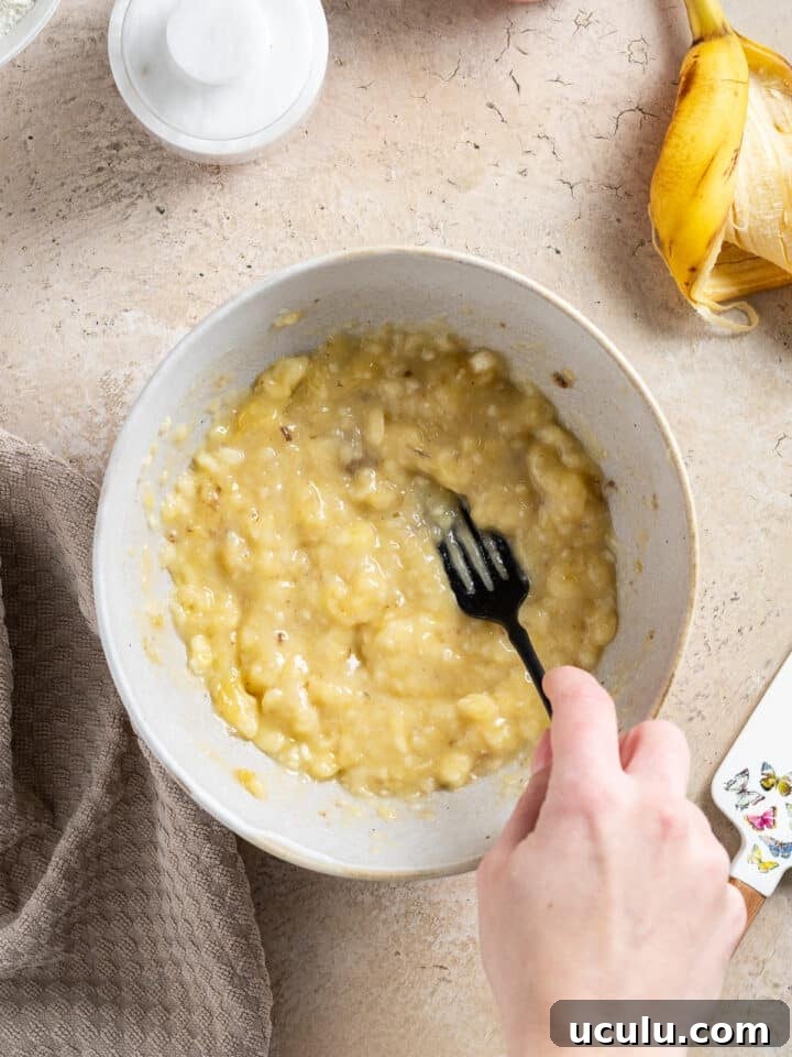 hand using a fork to mash bananas