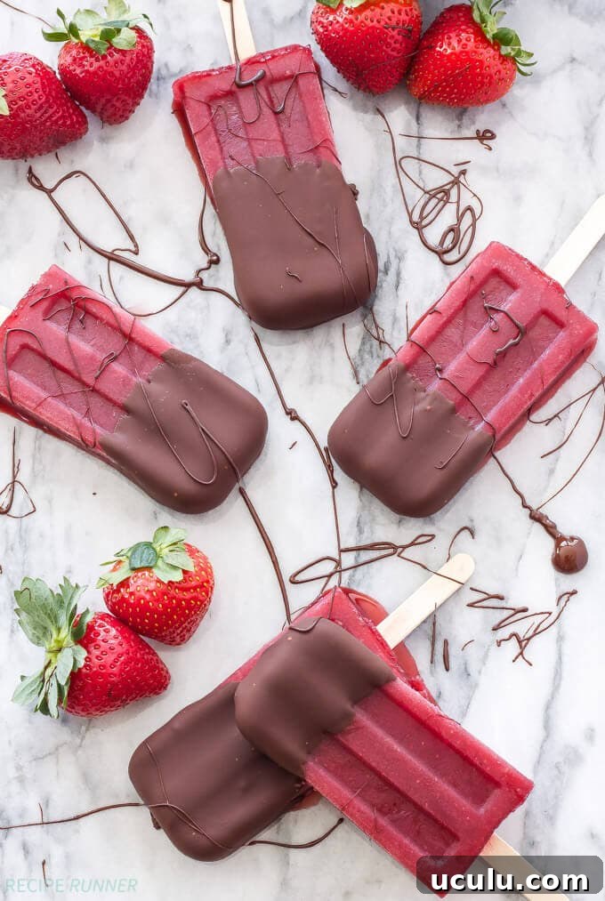 Five popsicles sitting on a white background with strawberries.
