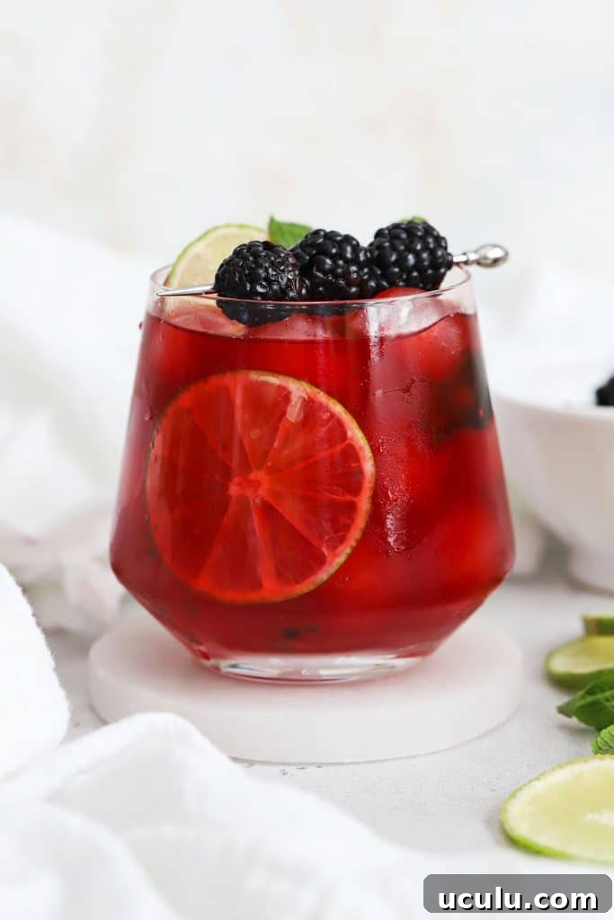 short glass of blackberry limeade garnished with fresh mint and blackberries