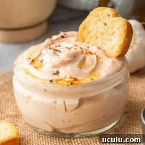 Square close up of pink-orange thick sayce in a glass jar with toasted bread stuck in it.