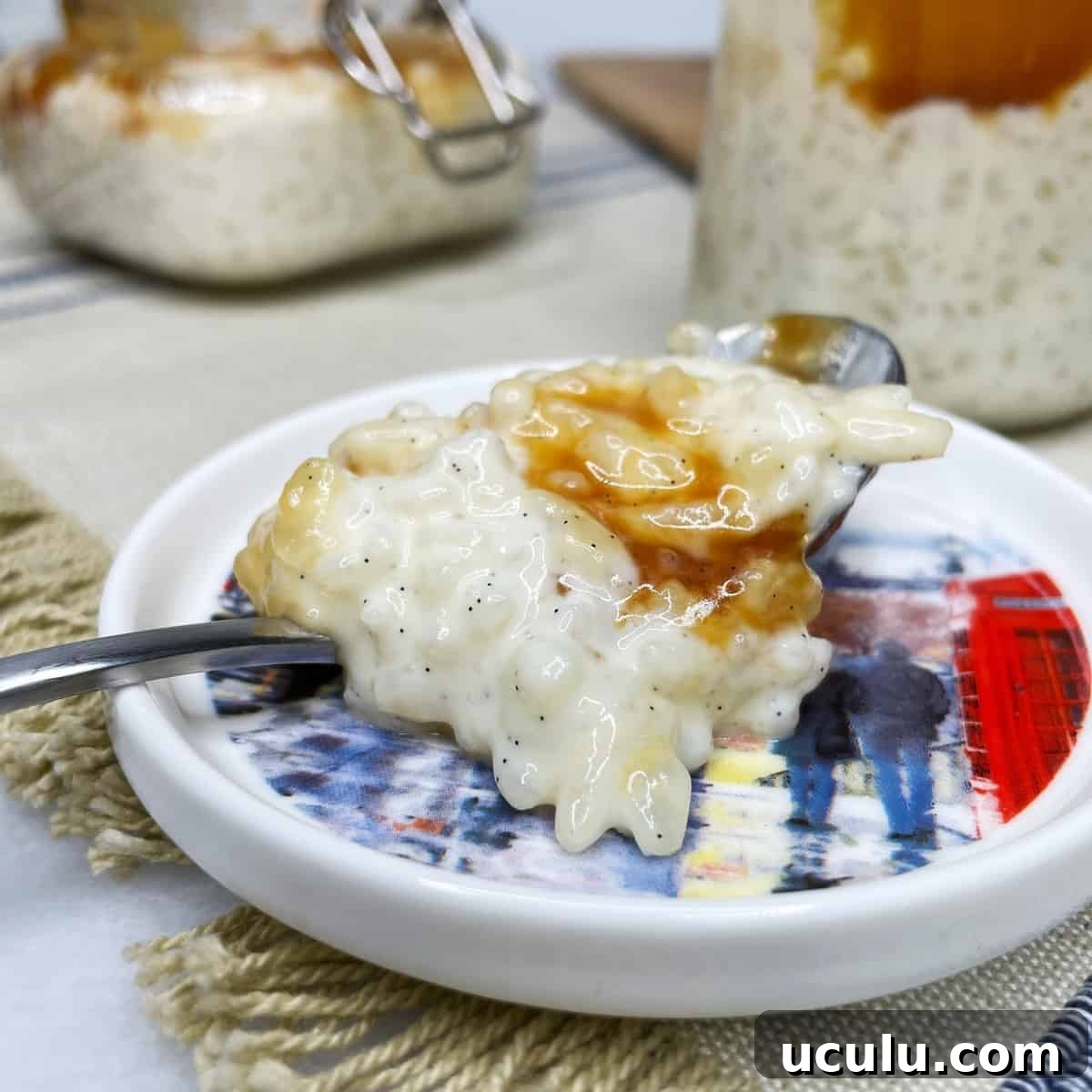 A spoon with rice pudding and caramel with jars in the background 