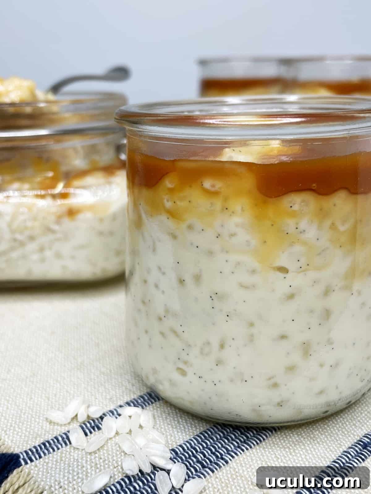 Three glass jars with riz au lair topped with salted butter caramel