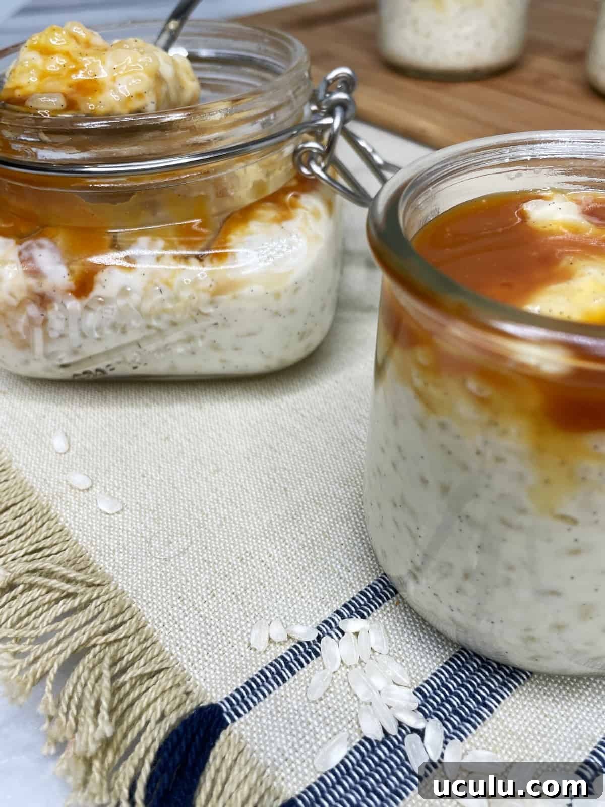 Two glass jars with rice pudding and rice grains in the background