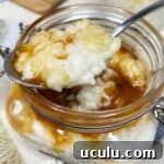 Glass jar with a spoon full of French rice pudding topped with caramel.