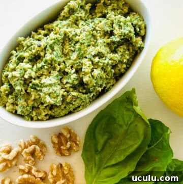 pesto recipe without pine nuts next to walnuts, basil and fresh lemon.