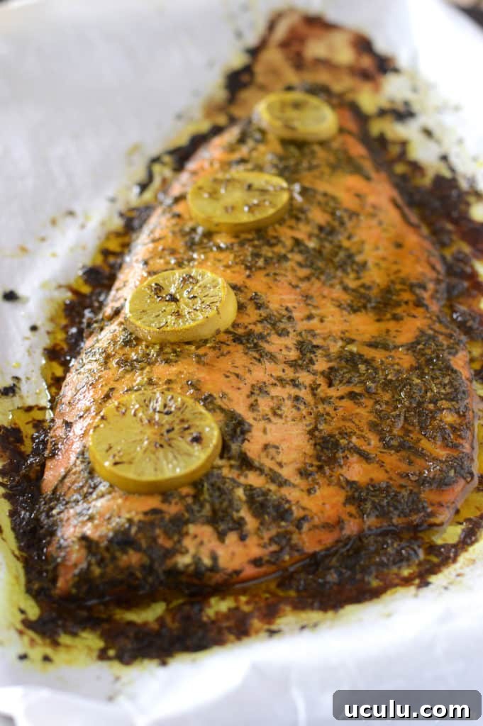 A whole salmon fish placed on a baking sheet and garnished with lemon rings