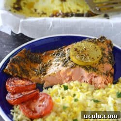 a piece of baked salmon with yellow rice on a blue plate