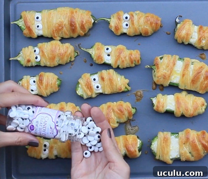 Placing candy eyes onto baked Jalapeno Popper Mummies that have just come out of the oven. 