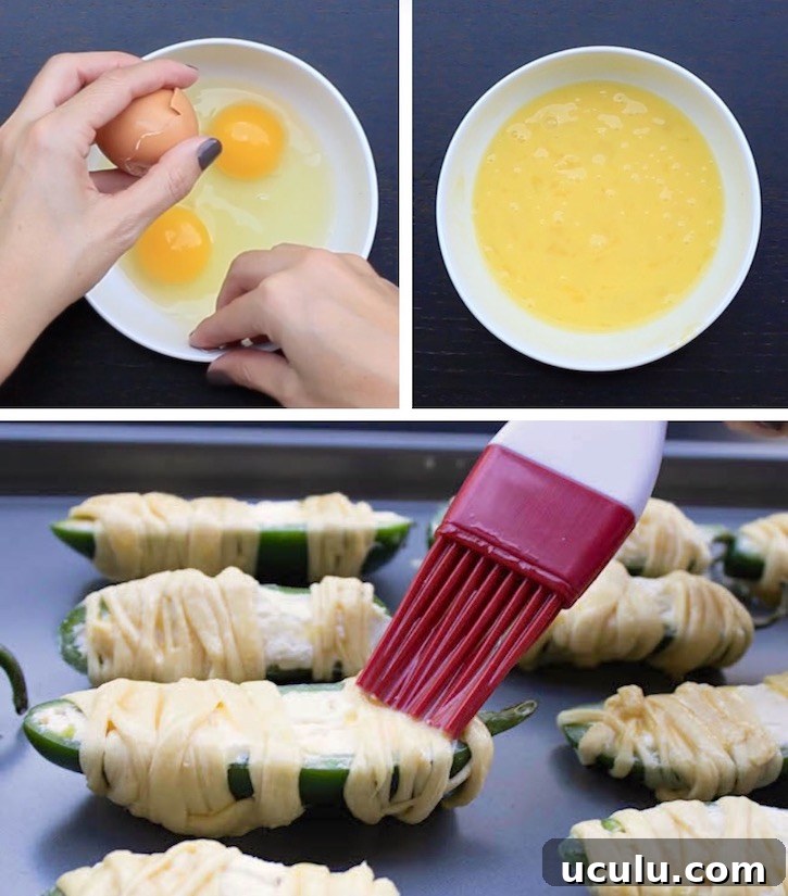 Brushing egg wash onto cream cheese stuffed Jalapeno peppers wrapped in thin strips of dough to make a fun and easy Halloween appetizer for parties. 