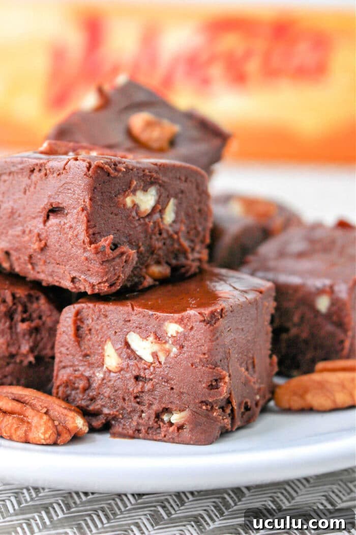 Close-up of chocolate fudge with Velveeta and pecan pieces stacked on a plate.