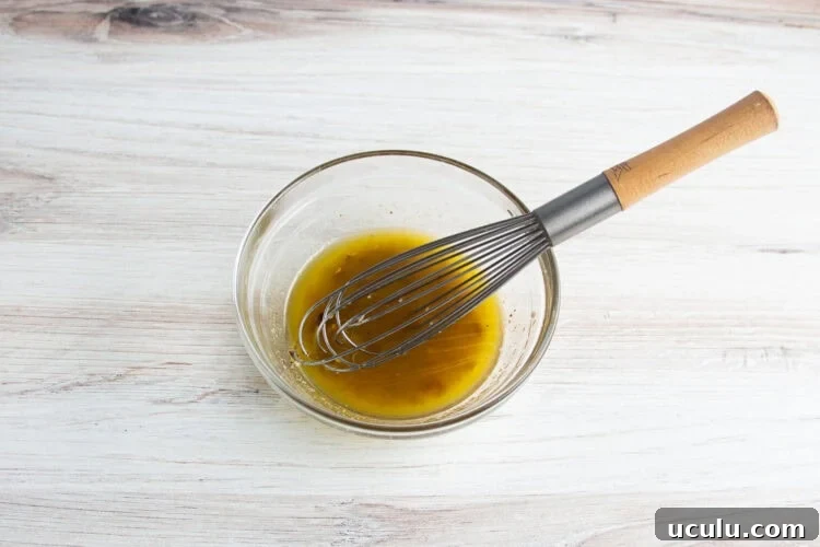 Overhead view of olive oil marinade for grilled broccolini in a glass mixing bowl.