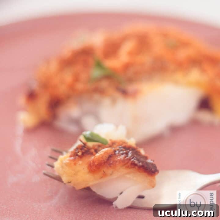 A square picture with cod with a cheese breadcrumb topping. A fork took a bite.