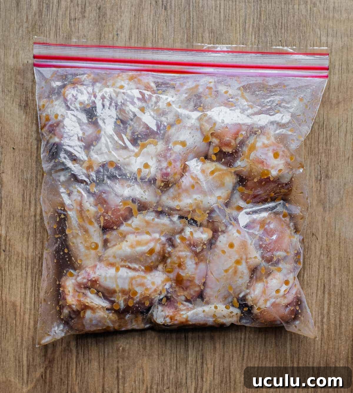 A plastic bag holding chicken wings in a Chinese marinade