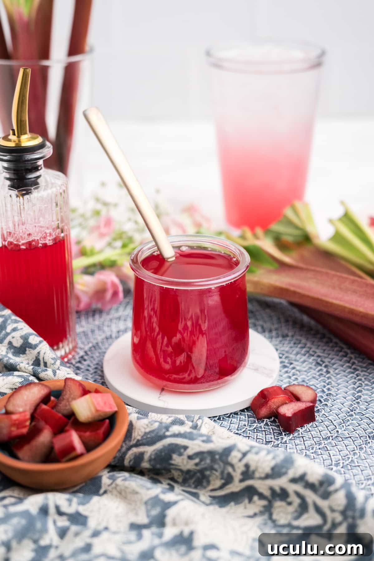 A jar of fresh rhubarb syrup with a gold spoon in it.