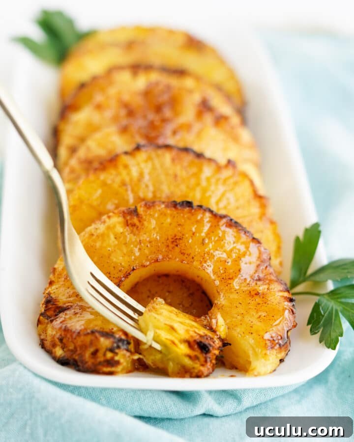 Caramelized pineapple rings on white platter with fork