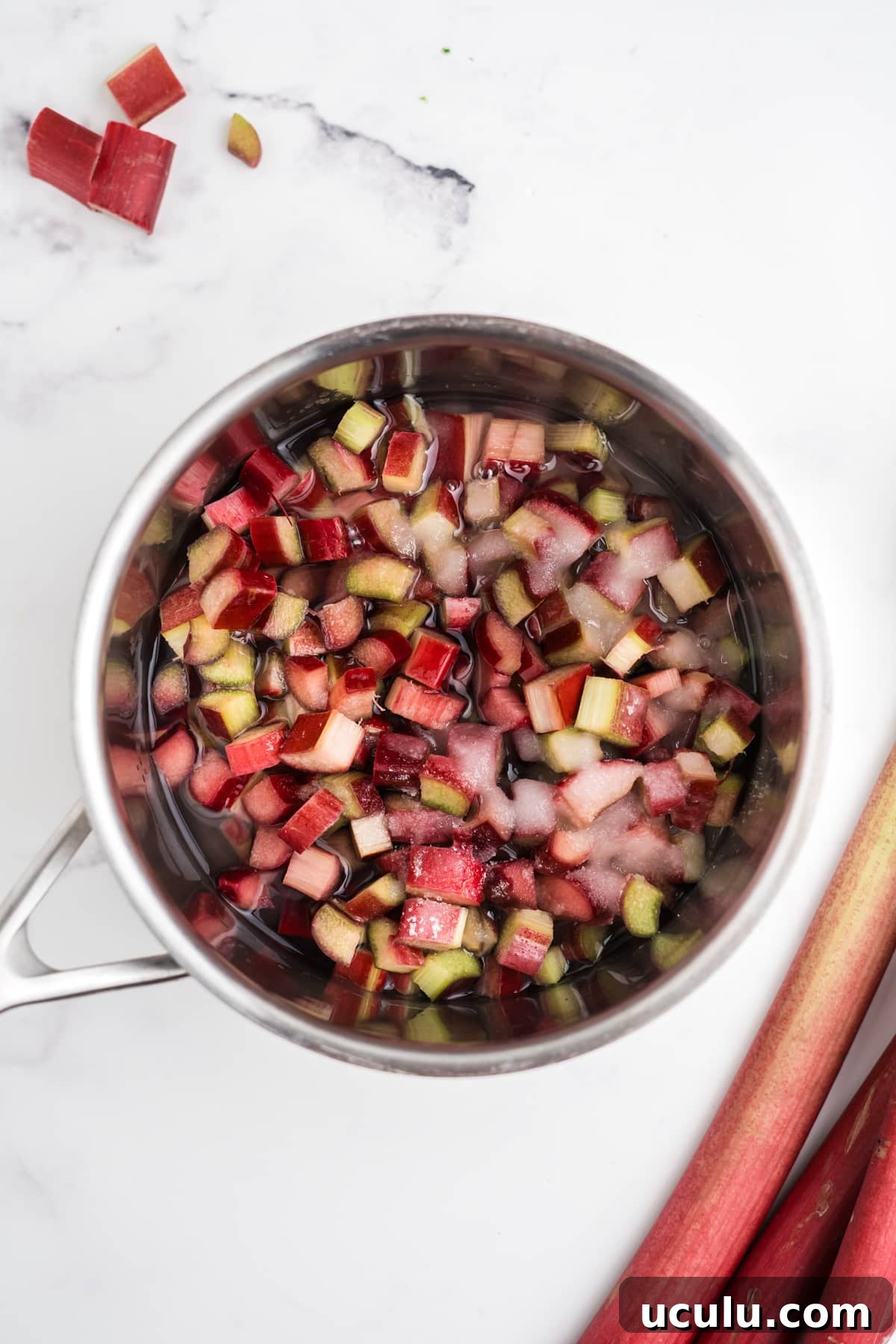 Rhubarb and sugar simmering in a saucepan.
