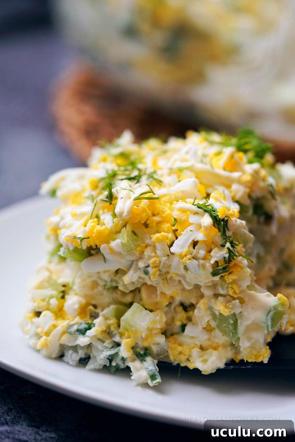 Close up shot of potato and egg salad assembled with mayo and arranged in layers, served cut with a spatula.