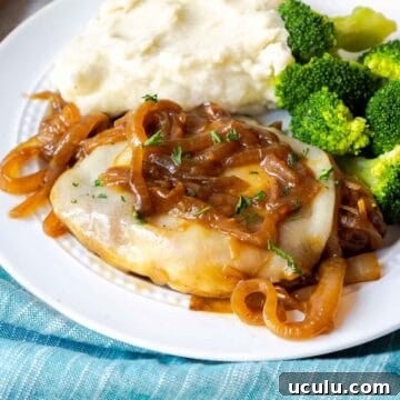 A pork chop topped with provolone and onions on a plate with mashed potatoes and broccoli.