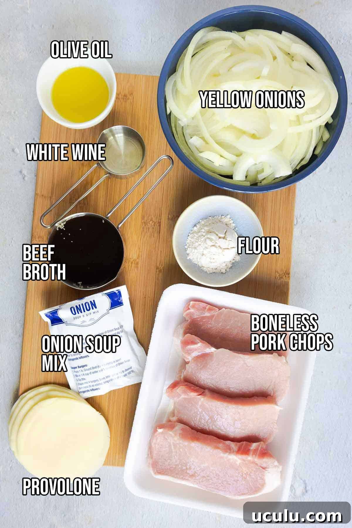Ingredients on a board including pork chops, sliced onions, olive oil, white wine, beef broth, flour, provolone, and onion soup mix. Text on the image says 'OLIVE OIL', 'WHITE WINE', 'BEEF BROTH', 'ONION SOUP MIX', 'PROVOLONE', 'FLOUR', 'YELLOW ONIONS', 'BONELESS PORK CHOPS'.