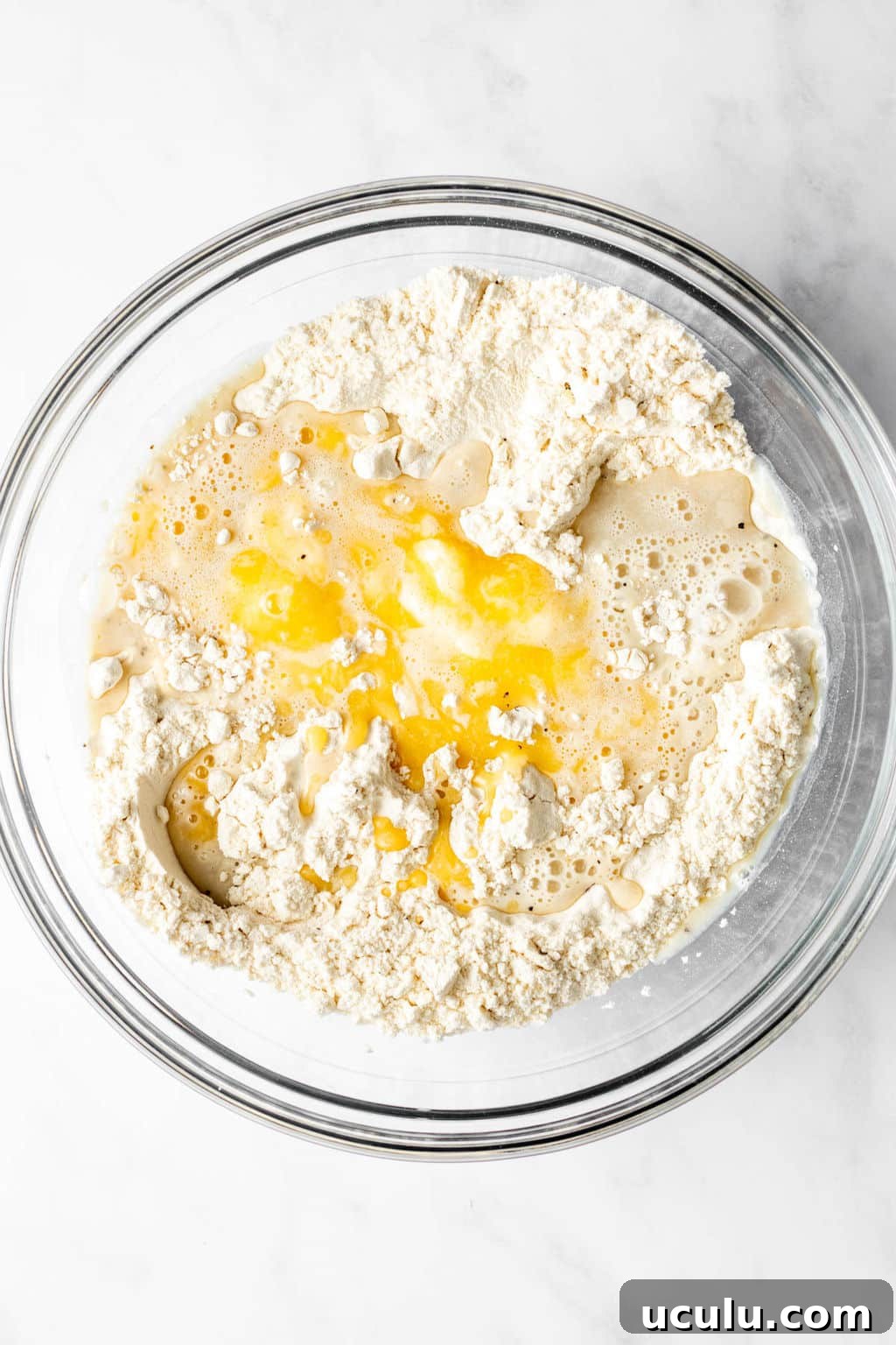 large glass bowl filled with flour, melted butter, and milk.