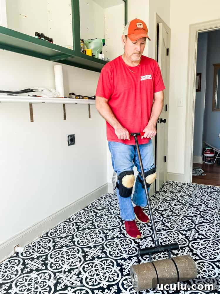 Man using a weighted roller to helppeel and stick vinyl tiles to adhere after being installed.