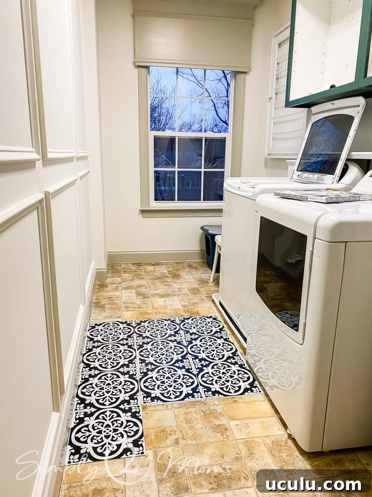 Laundry room with washer and dryer along the wall with peel and stick wallpops floor tiles laid on the floor to estimate installation pattern.
