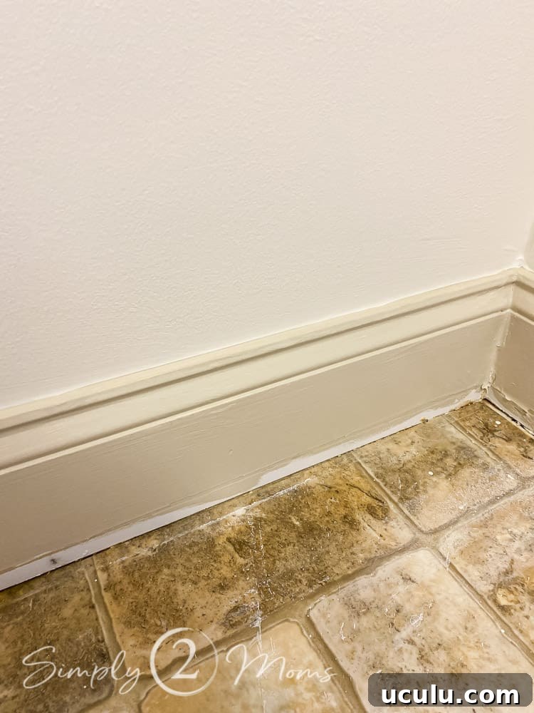 Close up of linoleum floor and baseboards after the quarter round moulding is removed.