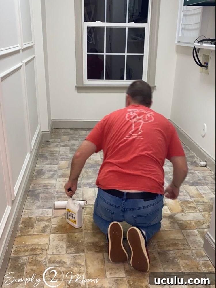 A man using a paint roller to apply adhesive primer for peel and stick flooring application