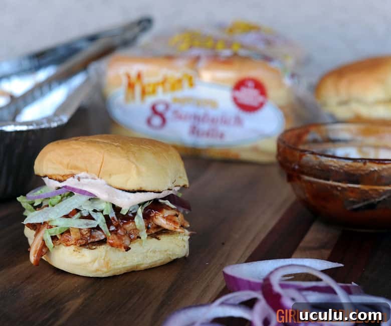 pulled chicken with bbq sauce on potato roll with shredded lettuce.
