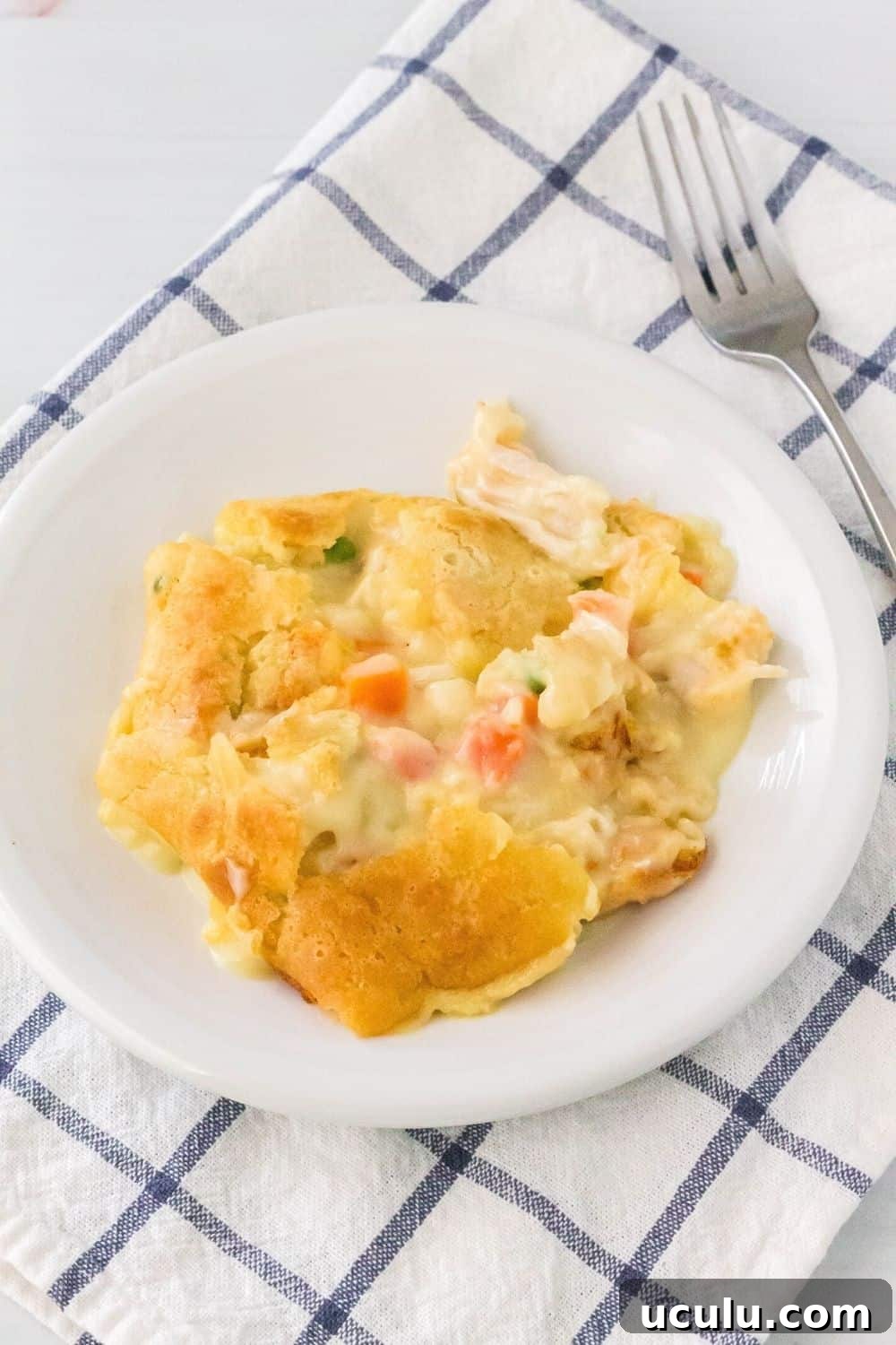 a serving of easy chicken cobbler casserole on a white plate, with a fork next to it