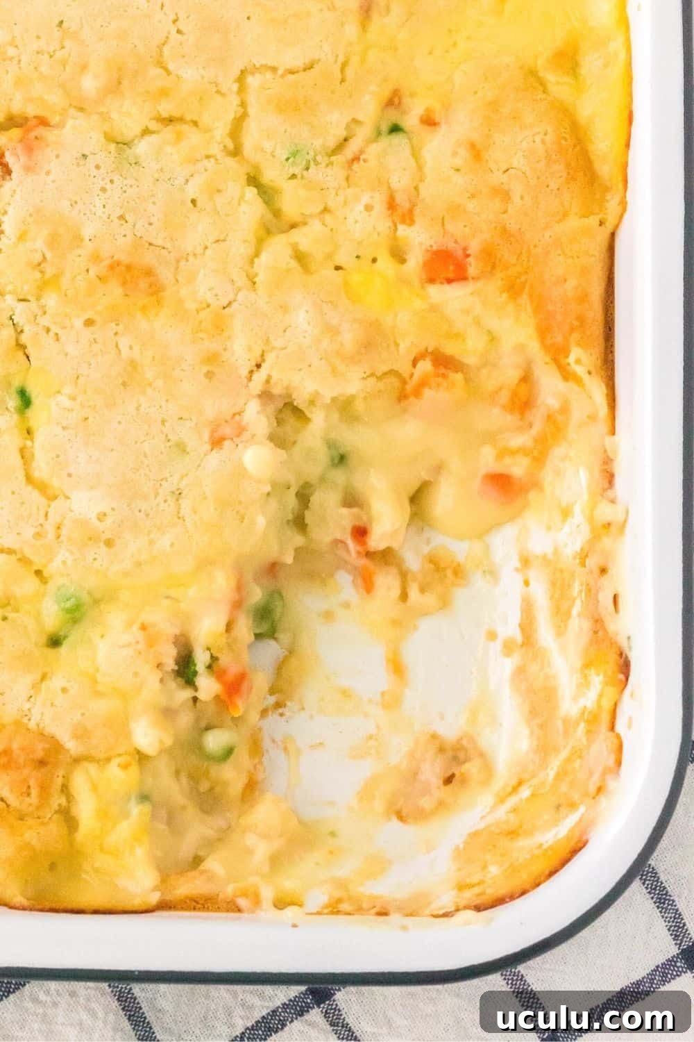 overhead view of a pan of cobbler-like chicken pot pie casserole, with some of the cobbler scooped out