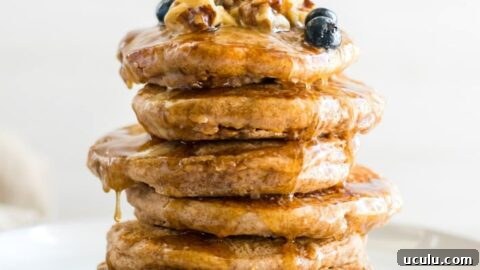 A stack of vegan pancakes topped with berries and maple syrup.