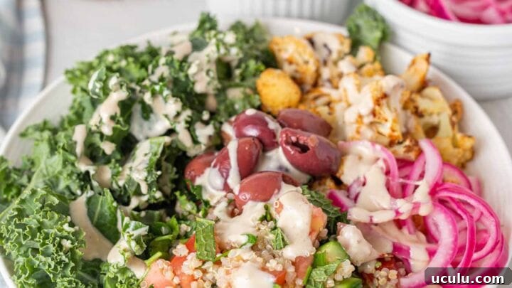 A bright bowl of healthy ingredients pickled onions, cauliflower, quinoa, kale and olives.