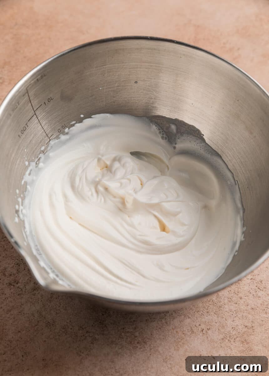 Heavy whipping cream in bowl beaten to stiff peaks.