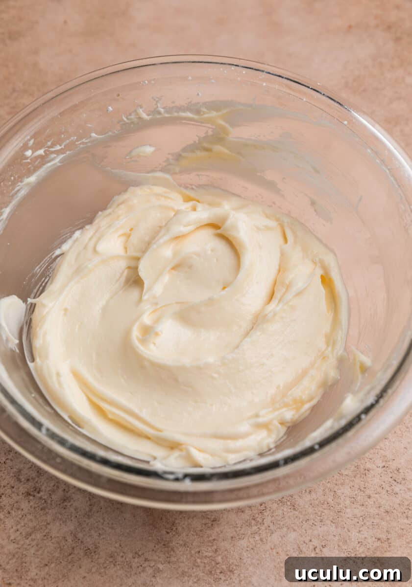 Cream cheese and sugar mixture creamed together in glass mixing bowl.