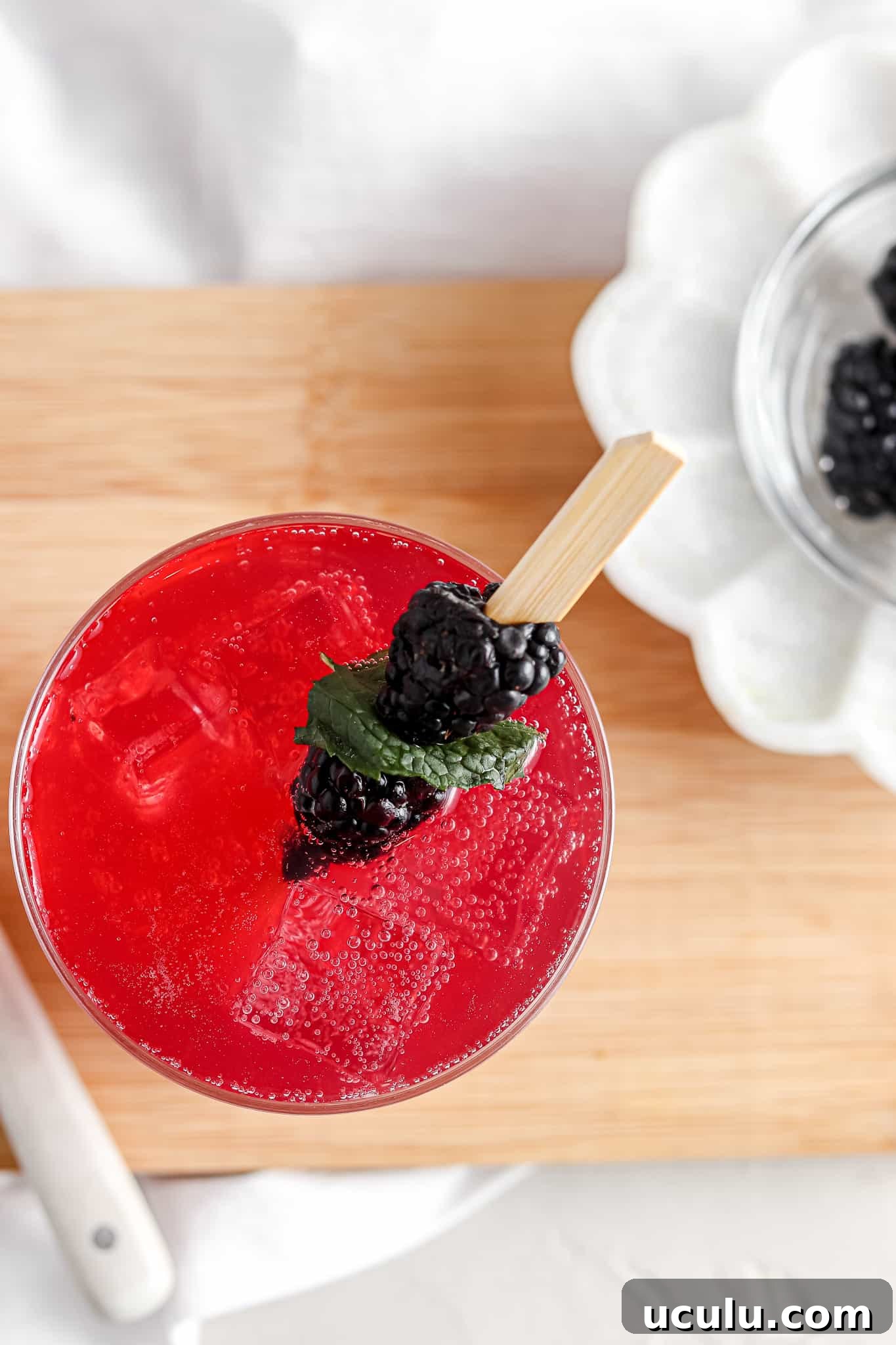 Overhead shot of a blackberry mojito in a glass with blackberries on top.